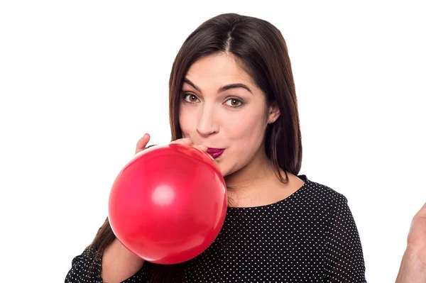 Mulher soprando um balão vermelho — Fotografia de Stock