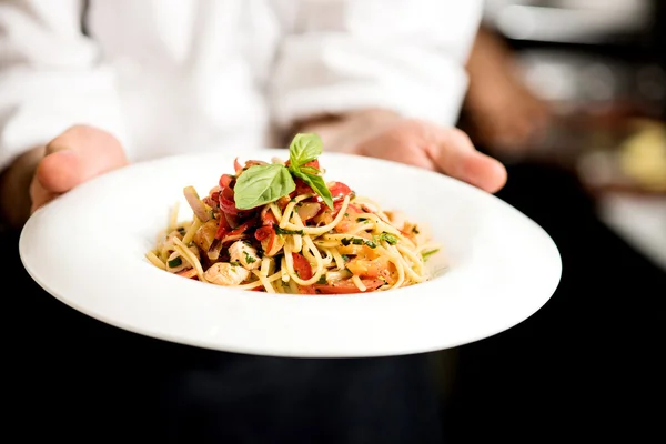 Chef mano tenendo piatto di pasta — Foto Stock