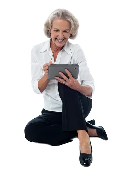 Elderly woman operating digital tablet — Stockfoto