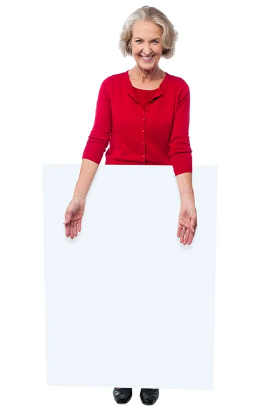 Aged woman standing behind blank billboard — Stock Photo, Image