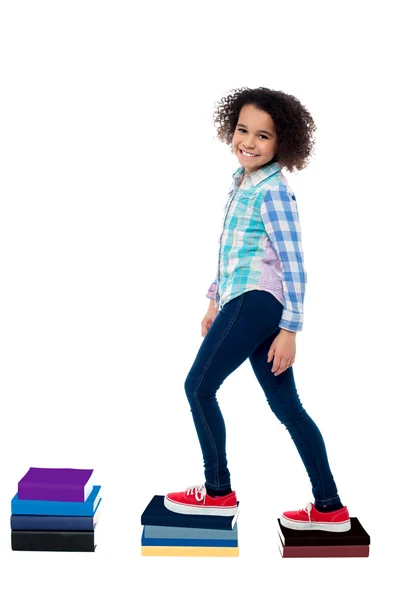 Menina criança escalando em cadernos — Fotografia de Stock