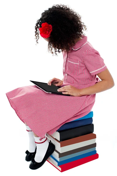 Meisje, zittend op boeken met digitale tablet — Stockfoto
