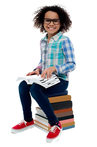 Chica sentada en la pila de libros — Foto de Stock