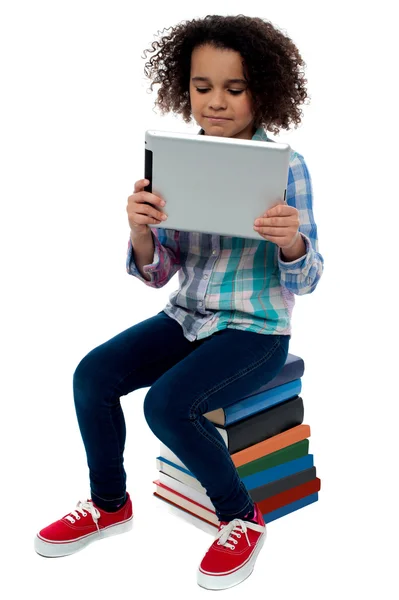 Mädchen sitzt auf Büchern mit digitalem Tablet — Stockfoto