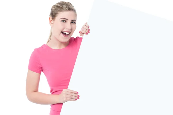 Teen girl posing behind an ad board — Stock Photo, Image