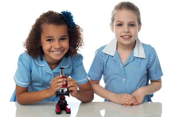 Dos colegialas practicando con microscopio — Foto de Stock