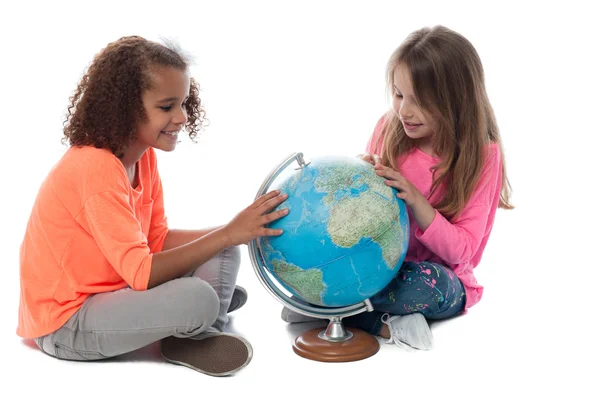 Zwei kleine Mädchen erkunden einen Globus — Stockfoto