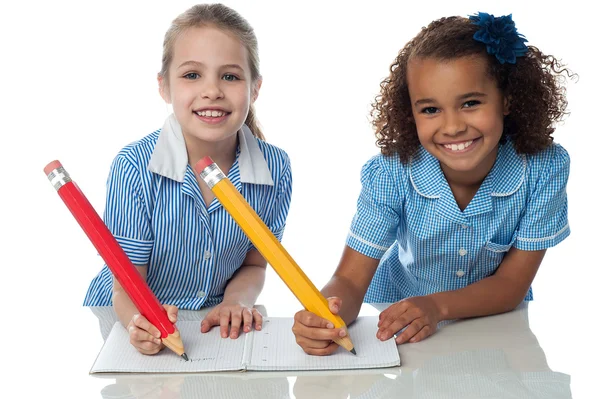 Schoolmeisjes schrijven huiswerk samen — Stockfoto