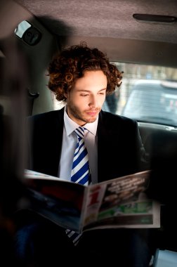 businessman reading newspaper inside taxi