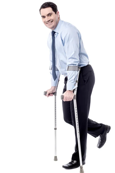 Businessman tying to walk with crutches — Stock Photo, Image