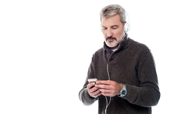 Senior man listening music on cell phone — Stock Photo, Image