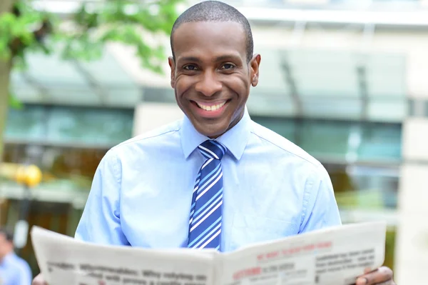 Geschäftsmann lächelt mit Zeitung — Stockfoto