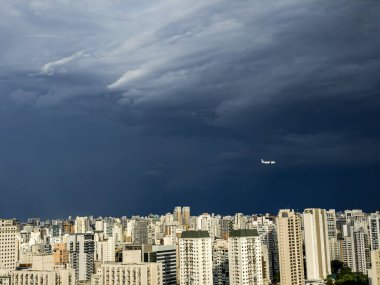 Birçok bina, yağmur bulutları ve geçen uçaklar. Sao Paulo şehri, Brezilya.