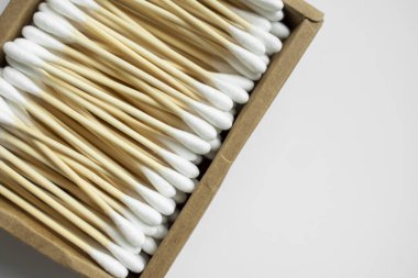 Çevre dostu pamuklu çubuklar. Gri bir yüzey üzerinde geri dönüşümlü bambu tomurcukları içeren karton bir kutu. Sıfır atık. Eko ürün. Kozmetik çubuklar kutuda. Kulakları temizlemek için tahta sopalar..