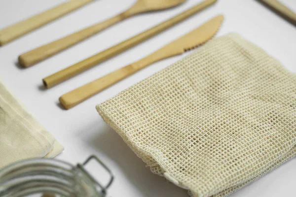 Sıfır atık. Çevre dostu bambu çatal bıçak takımı, ağ pamuk torbaları, cam kavanozlar ve lif süngeri. Plastiksiz. Gri yüzeyde doğal ve yeniden kullanılabilir öğeler aksesuarları.
