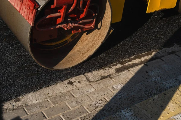 Asphalt road roller with heavy vibration roller compactor press new hot asphalt on the roadway on a road construction site. Heavy Vibration roller at asphalt pavement working. Repairing.