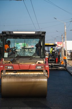 Ağır titreşimli paten sıkıştırıcılı asfalt yol silindiri bir yol inşaatındaki yolda yeni bir sıcak asfalta bastırıyor. Asfalt kaldırımda ağır titreşimli silindir çalışıyor. Onarılıyor.