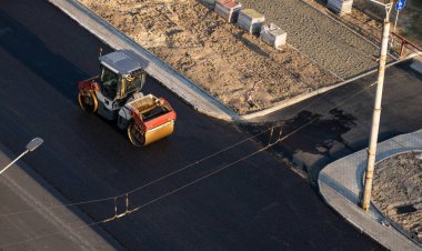 Ağır titreşimli paten sıkıştırıcılı asfalt yol silindiri bir yol inşaatındaki yolda yeni bir sıcak asfalta bastırıyor. Asfalt kaldırımda ağır titreşimli silindir çalışıyor. Onarılıyor.