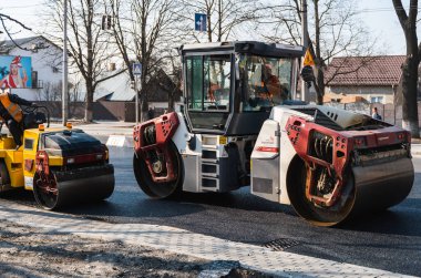 KYIV, UKRAINE - 10 Eylül 2020: Ağır asfalt yol silindirli ağır titreşimli paten sıkıştırıcısı, bir cadde üzerindeki yol inşaatında yeni bir sıcak asfalta baskı yapıyor..