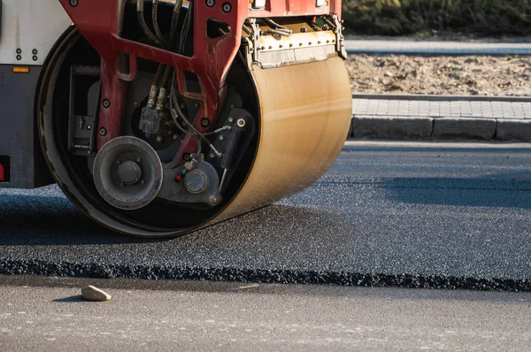 Asphalt road roller with heavy vibration roller compactor press new hot asphalt on the roadway on a road construction site. Heavy Vibration roller at asphalt pavement working. Repairing.