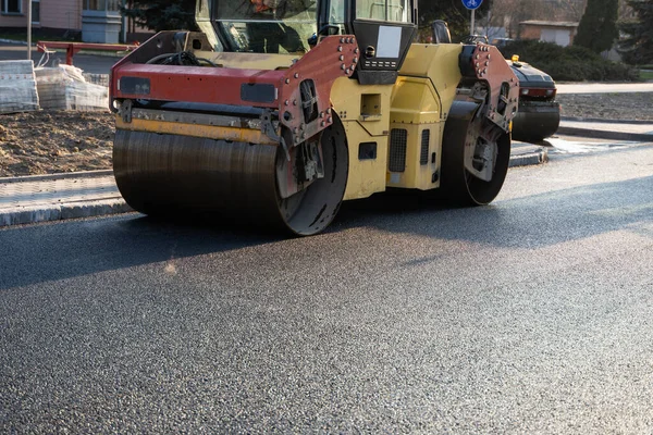 Asphalt road roller with heavy vibration roller compactor press new hot asphalt on the roadway on a road construction site. Heavy Vibration roller at asphalt pavement working. Repairing. — Stock Photo, Image