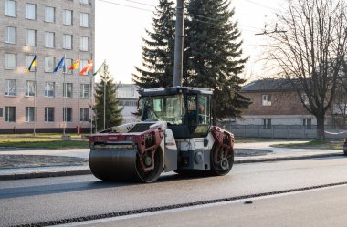 KYIV, UKRAINE - 10 Eylül 2020: Ağır asfalt yol silindirli ağır titreşimli paten sıkıştırıcısı, bir cadde üzerindeki yol inşaatında yeni bir sıcak asfalta baskı yapıyor..