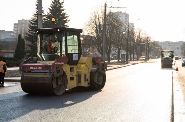 KYIV, UKRAINE - 10 Eylül 2020: Ağır asfalt yol silindirli ağır titreşimli paten sıkıştırıcısı, bir cadde üzerindeki yol inşaatında yeni bir sıcak asfalta baskı yapıyor..