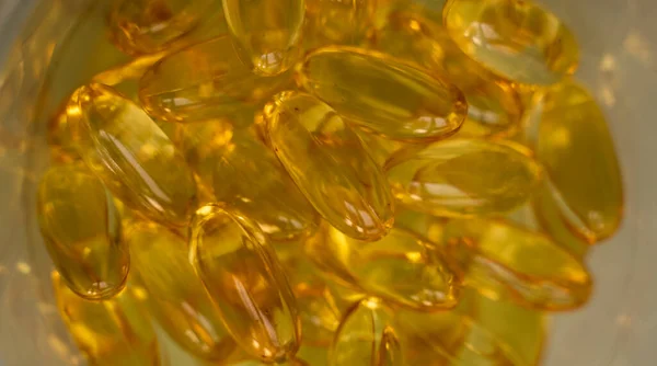 Extremo close-up de óleo de peixe laranja amarelo softgels cápsulas óleo de peixe ômega 3 ou ômega 6, ômega 9, vitamina A, vitamina D, fundo de vitamina E. Conceito de produto de vitaminas saudáveis. — Fotografia de Stock