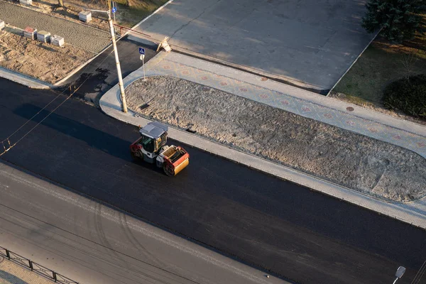 Asphalt road roller with heavy vibration roller compactor press new hot asphalt on the roadway on a road construction site. Heavy Vibration roller at asphalt pavement working. Repairing.