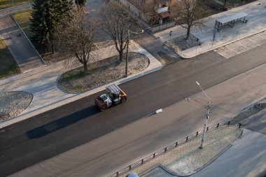 Ağır titreşimli paten sıkıştırıcılı asfalt yol silindiri bir yol inşaatındaki yolda yeni bir sıcak asfalta bastırıyor. Asfalt kaldırımda ağır titreşimli silindir çalışıyor. Onarılıyor.