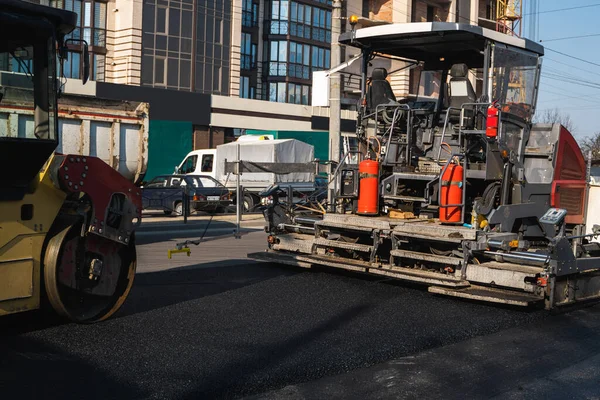 Przemysłowa nawierzchnia asfaltowa układanie świeżego asfaltu i ciężkiego walca drogowego z wibracji rolki zagęszczarki naciśnij nowy gorący asfalt na budowie drogi. — Zdjęcie stockowe