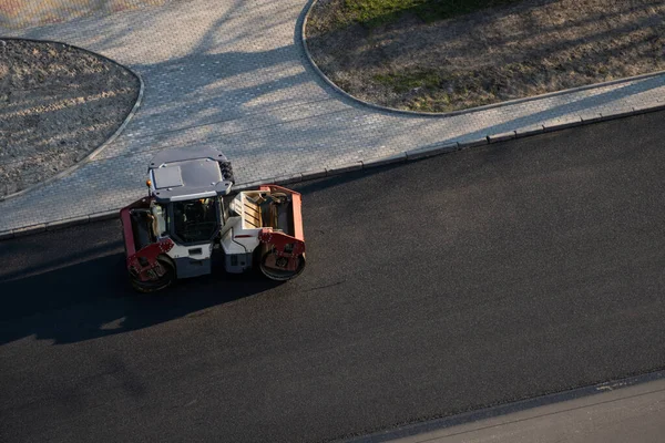 Asphalt road roller with heavy vibration roller compactor press new hot asphalt on the roadway on a road construction site. Heavy Vibration roller at asphalt pavement working. Repairing. — Stock Photo, Image