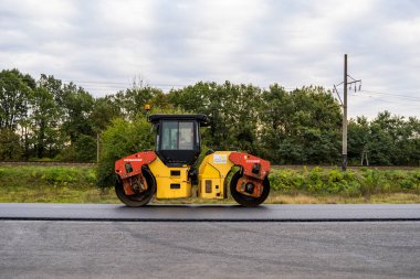 KYIV, UKRAINE - 25 Eylül 2020: İki ağır asfalt yol silindiri ve ağır titreşimli paten sıkıştırıcısı bir cadde üzerindeki yol inşaatında yeni bir sıcak asfalta baskı yapıyor..