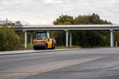 KYIV, UKRAINE - 25 Eylül 2020: İki ağır asfalt yol silindiri ve ağır titreşimli paten sıkıştırıcısı bir cadde üzerindeki yol inşaatında yeni bir sıcak asfalta baskı yapıyor..