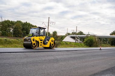 KYIV, UKRAINE - 25 Eylül 2020: Ağır sarı asfalt yol silindirli ağır titreşimli paten sıkıştırıcı bir caddedeki yol inşaatında yeni bir sıcak asfalta basıyor.