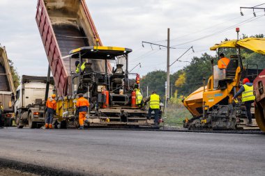KYIV, UKRAINE - 25 Eylül 2020: Karayolu şantiyesine yeni asfalt döşeyen endüstriyel asfalt kaldırım makinesi.