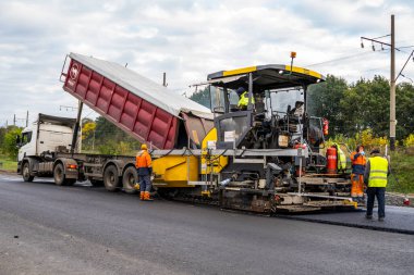 KYIV, UKRAINE - 25 Eylül 2020: Karayolu şantiyesine yeni asfalt döşeyen endüstriyel asfalt kaldırım makinesi.