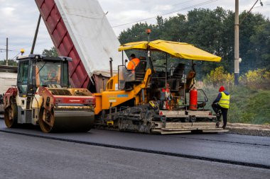 KYIV, UKRAINE - 25 Eylül 2020: Karayolu şantiyesine yeni asfalt döşeyen endüstriyel asfalt kaldırım makinesi.