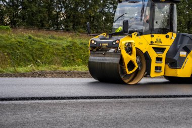 KYIV, UKRAINE - 25 Eylül 2020: Ağır sarı asfalt yol silindirli ağır titreşimli paten sıkıştırıcı bir caddedeki yol inşaatında yeni bir sıcak asfalta basıyor.