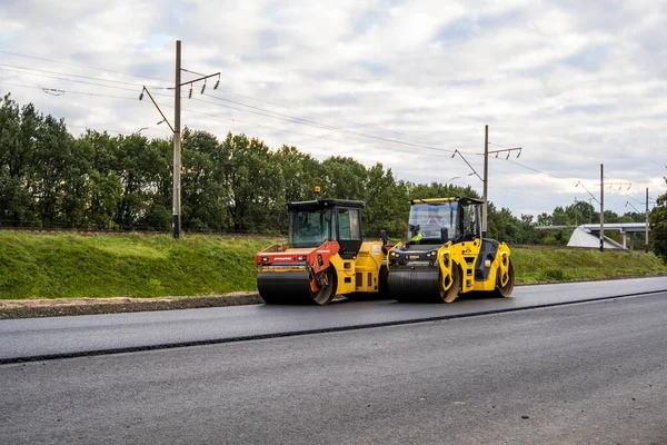 KYIV, UKRAINE - 25 września 2020: Dwa ciężkie asfaltowe rolki drogowe z ciężkim zagęszczaczem walców wibracyjnych, które naciskają nowy gorący asfalt na jezdni na placu budowy dróg na ulicy. — Zdjęcie stockowe