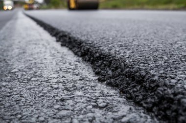 Ağır titreşimli paten sıkıştırıcılı asfalt yol silindiri bir yol inşaatındaki yolda yeni bir sıcak asfalta bastırıyor. Asfalt kaldırımda ağır titreşimli silindir çalışıyor. Onarılıyor.