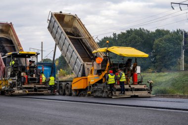 KYIV, UKRAINE - 25 Eylül 2020: Karayolu şantiyesine yeni asfalt döşeyen endüstriyel asfalt kaldırım makinesi.