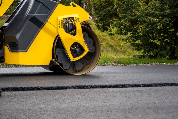 Asphalt road roller with heavy vibration roller compactor press new hot asphalt on the roadway on a road construction site. Heavy Vibration roller at asphalt pavement working. Repairing.