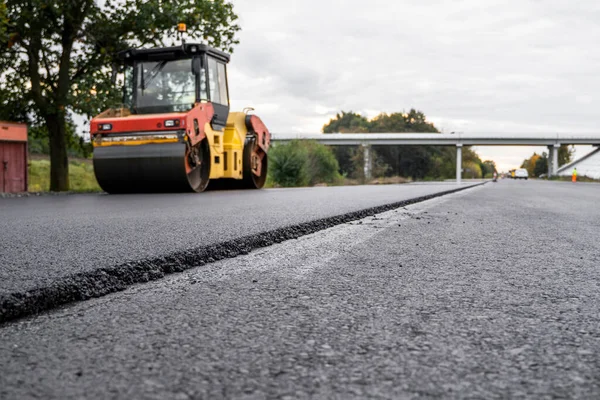 Asfalt road roller z ciężkimi wibracjami rolki zagęszczarki naciśnij nowy gorący asfalt na jezdni na placu budowy dróg. Ciężki wałek wibracyjny na asfaltowej nawierzchni działa. Naprawa. — Zdjęcie stockowe