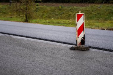 Büyük bir katman taze asfalt. Sığ bir alan derinliğinde asfalt ham madde tabakası. Patenler yeni yolda taze asfalt gibi yuvarlanıyor. Yol yapımı. Yeni bir yol inşaatı.