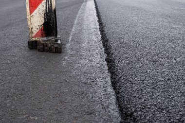 Büyük bir katman taze asfalt. Sığ bir alan derinliğinde asfalt ham madde tabakası. Patenler yeni yolda taze asfalt gibi yuvarlanıyor. Yol yapımı. Yeni bir yol inşaatı.