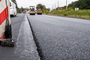 Büyük bir katman taze asfalt. Sığ bir alan derinliğinde asfalt ham madde tabakası. Patenler yeni yolda taze asfalt gibi yuvarlanıyor. Yol yapımı. Yeni bir yol inşaatı.