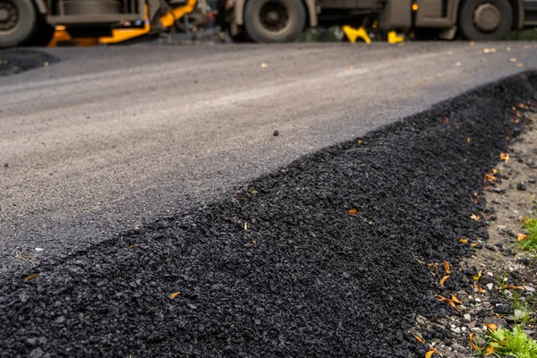 Velká vrstva čerstvého horkého asfaltu. Vrstva asfaltové suroviny v mělké hloubce pole. Válečky kutálí čerstvý horký asfalt na nové silnici. Výstavba silnice. Výstavba nové silnice. — Stock fotografie