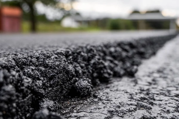 Velká vrstva čerstvého horkého asfaltu. Vrstva asfaltové suroviny v mělké hloubce pole. Válečky kutálí čerstvý horký asfalt na nové silnici. Výstavba silnice. Výstavba nové silnice. — Stock fotografie