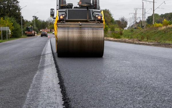 Asphalt road roller with heavy vibration roller compactor press new hot asphalt on the roadway on a road construction site. Heavy Vibration roller at asphalt pavement working. Repairing.